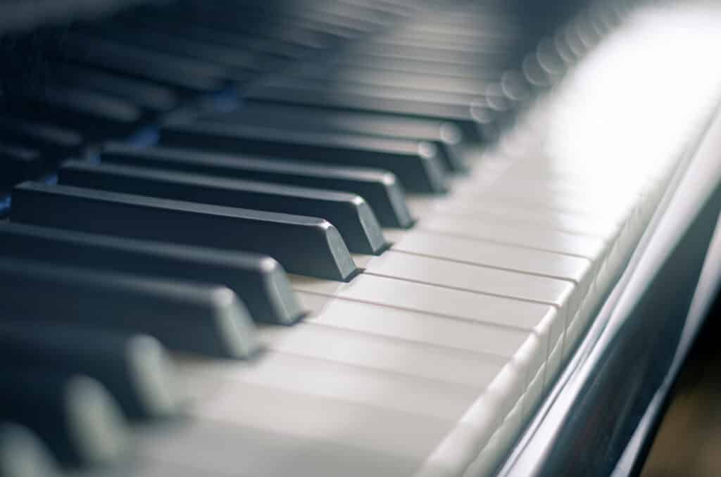 Clavier de piano numérique ou acoustique avec touches noires sombres et blanches lumineuses, effet bokeh subtil.
